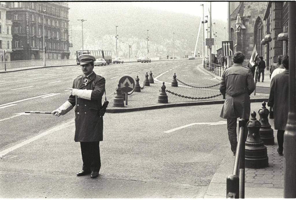 A Felszab(adulás) téren (ma: Ferenciek tere) kokárdás, díszegyenruhás rendőr biztosítja a felvonulók számára az utat.